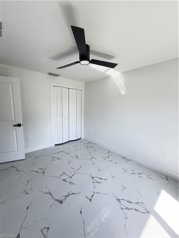 Unfurnished bedroom featuring a closet, a ceiling fan, and light marble finish flooring