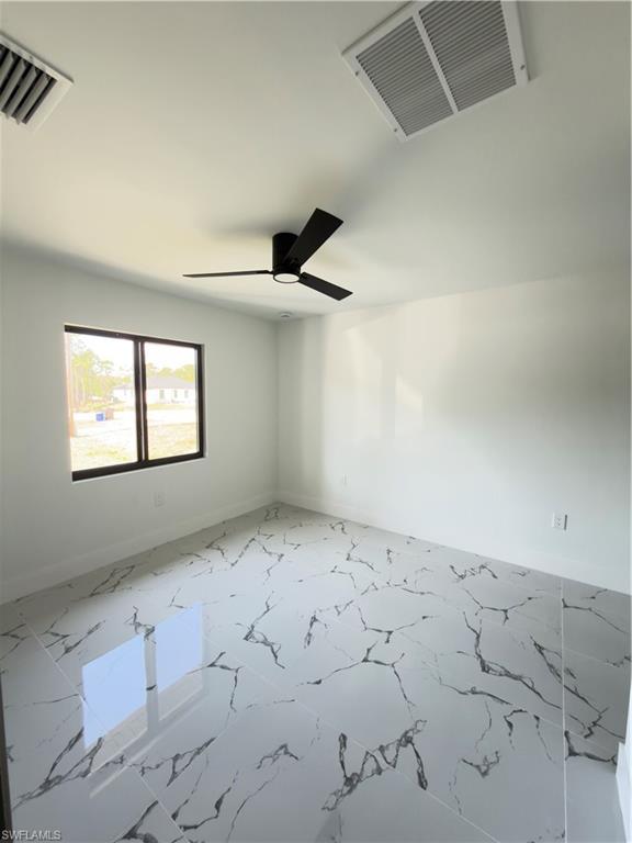 Spare room with ceiling fan and light marble finish floors