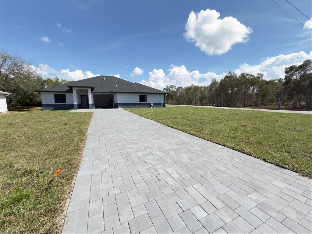 View of front of property featuring a front lawn, decorative driveway, and a garage