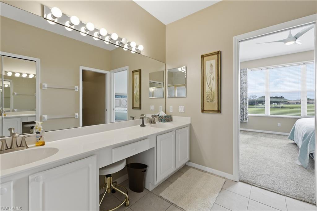 Bathroom featuring connected bathroom, double vanity, light colored carpet, light tile patterned floors, and ceiling fan