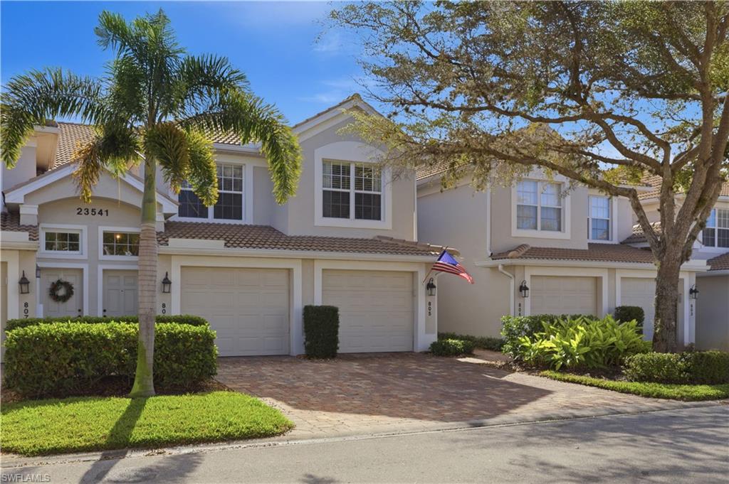 View of front facade featuring a garage, decorative driveway, a tile roof, and stucco siding