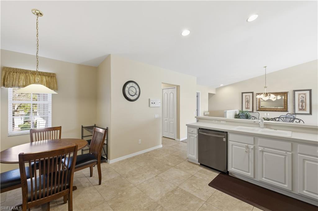 Kitchen featuring decorative light fixtures, dishwasher, light countertops, white cabinetry, and vaulted ceiling