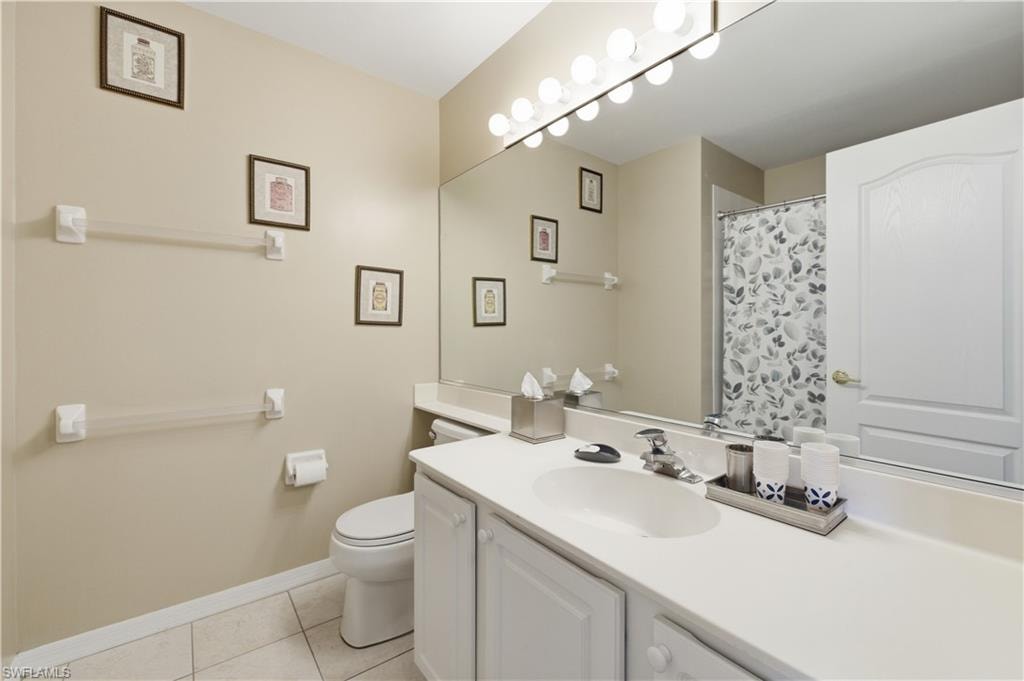 Full bath with vanity, a shower with shower curtain, and light tile patterned flooring