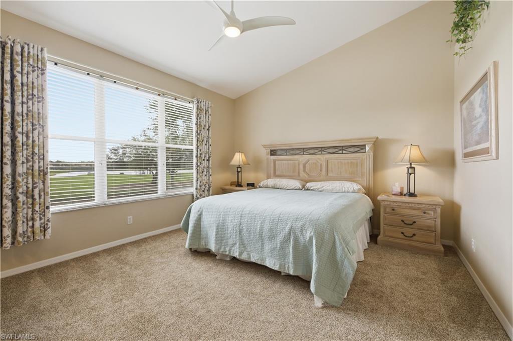 Bedroom with lofted ceiling, light carpet, and a ceiling fan