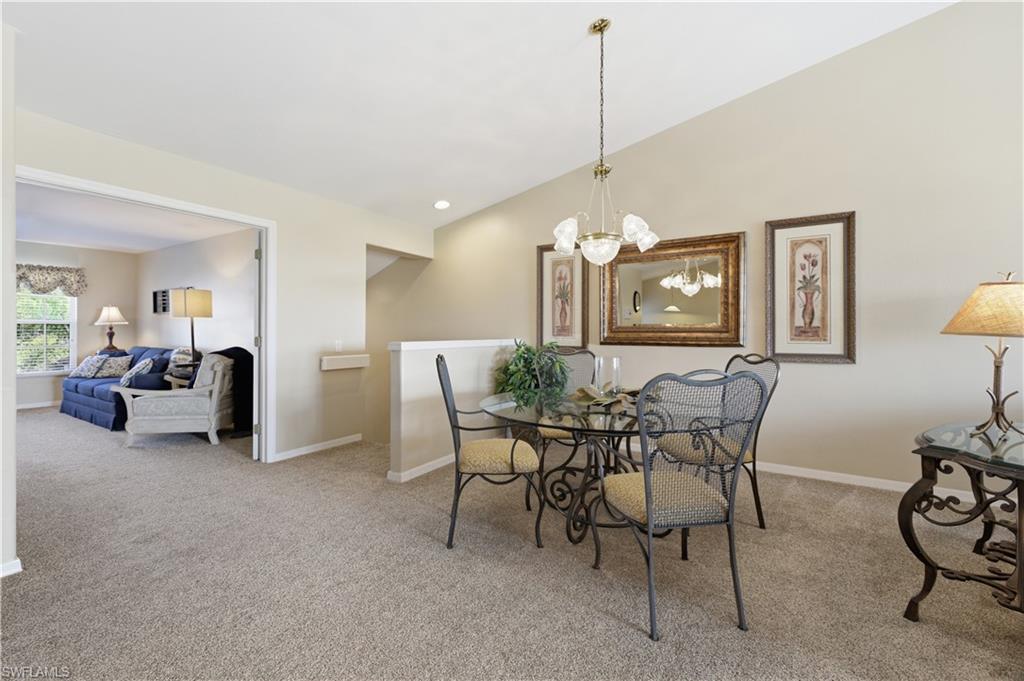 Dining room featuring light colored carpet, a chandelier, and vaulted ceiling