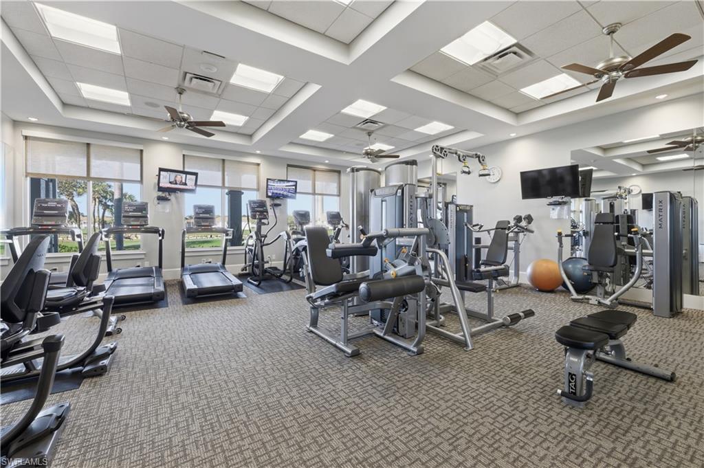 Workout area with a ceiling fan, a paneled ceiling, and a raised ceiling