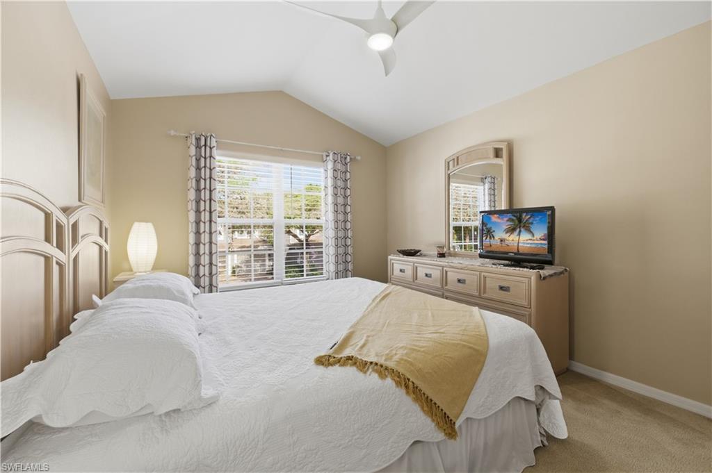 Bedroom featuring vaulted ceiling, light colored carpet, and a ceiling fan