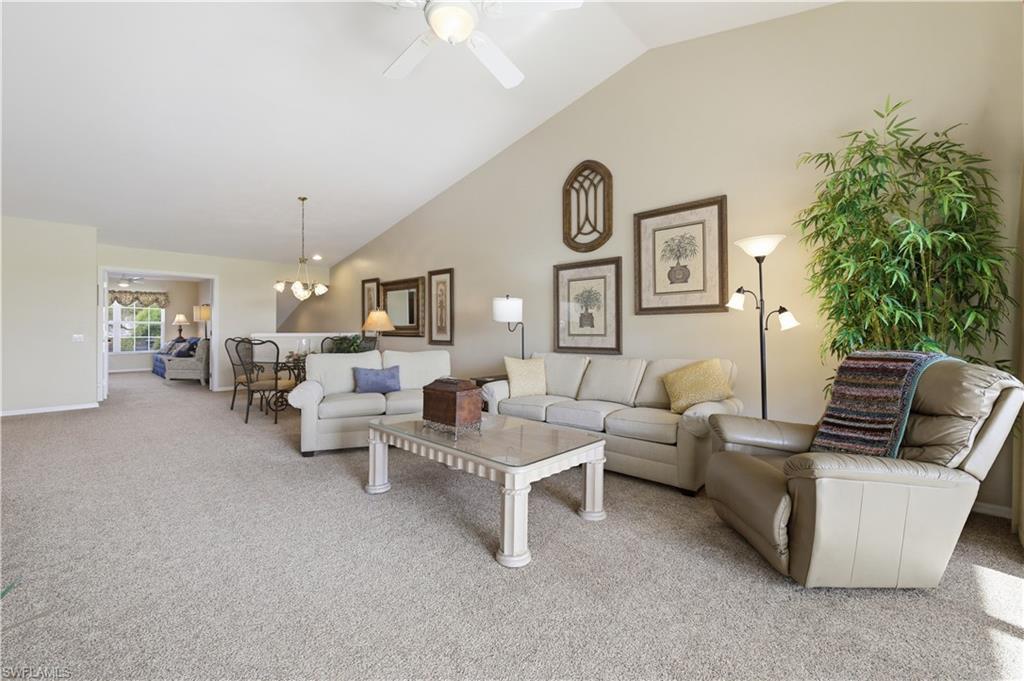 Carpeted living room with a ceiling fan, lofted ceiling, and a chandelier