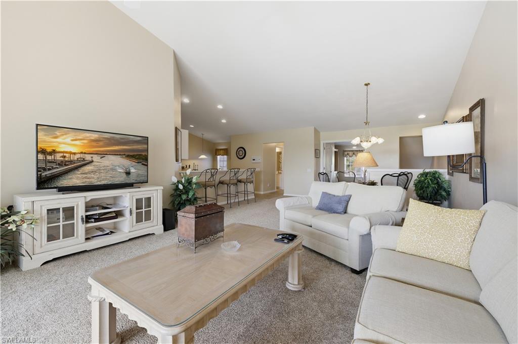 Living area featuring hanging lights, a high ceiling, and light carpet
