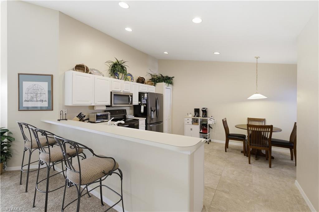 Kitchen with a breakfast bar, stainless steel appliances, light countertops, a peninsula, and white cabinetry
