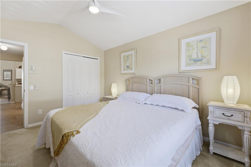 Bedroom with lofted ceiling, light carpet, a closet, and a ceiling fan