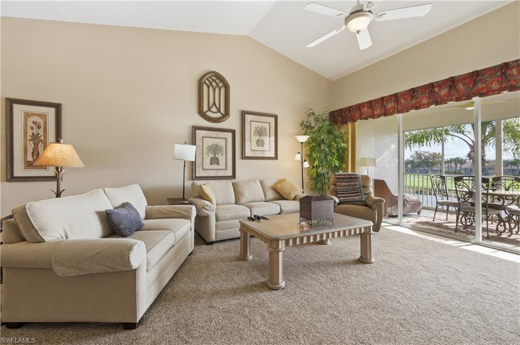 Carpeted living room featuring a ceiling fan and vaulted ceiling