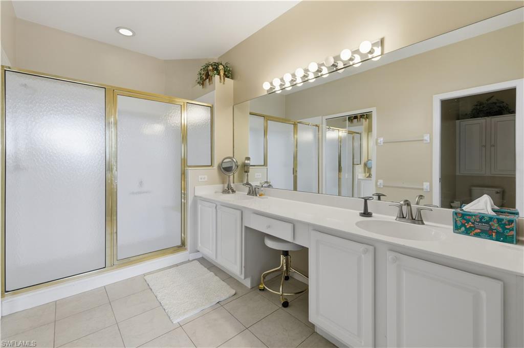 Full bath featuring double vanity, a shower stall, and light tile patterned floors