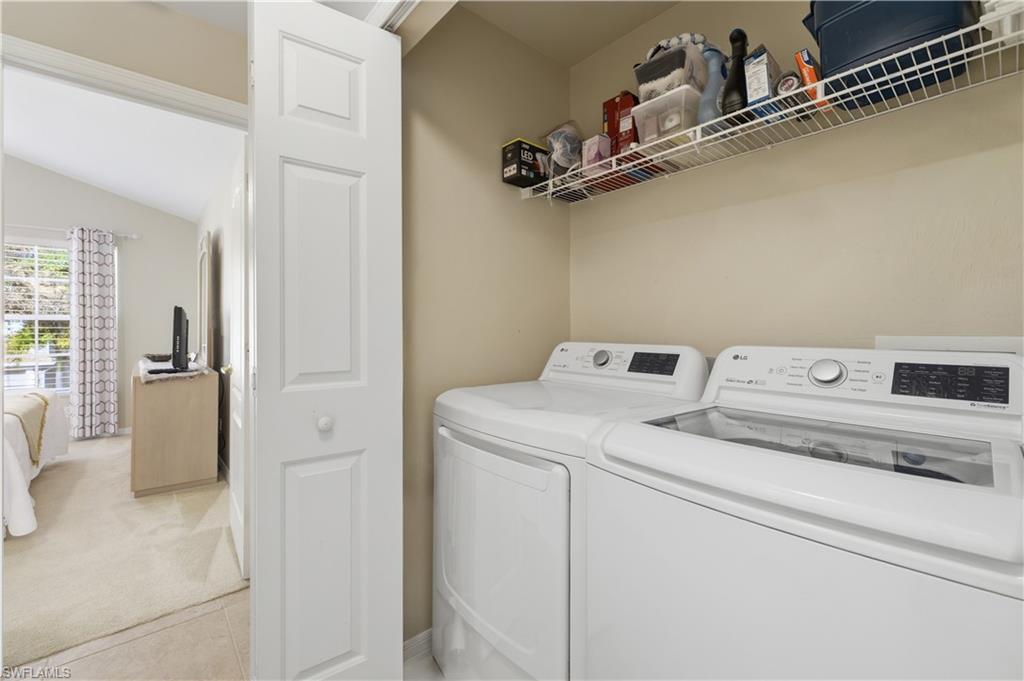 Laundry area with lofted ceiling, independent washer and dryer, light carpet, and light tile patterned floors