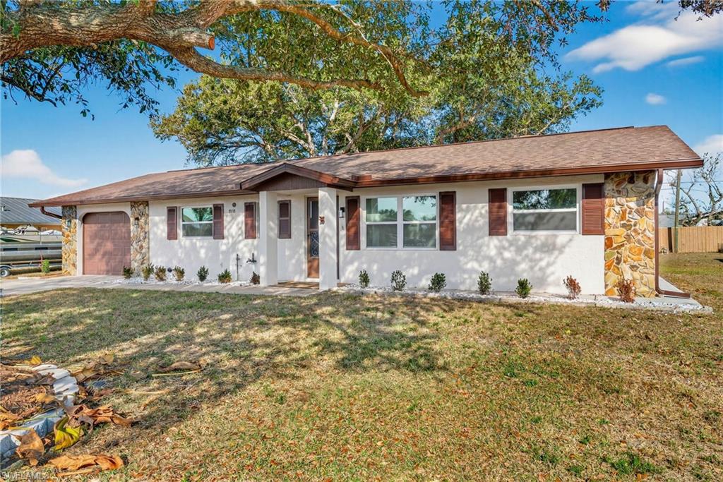 Single story home with stone siding, a garage, and roof with shingles