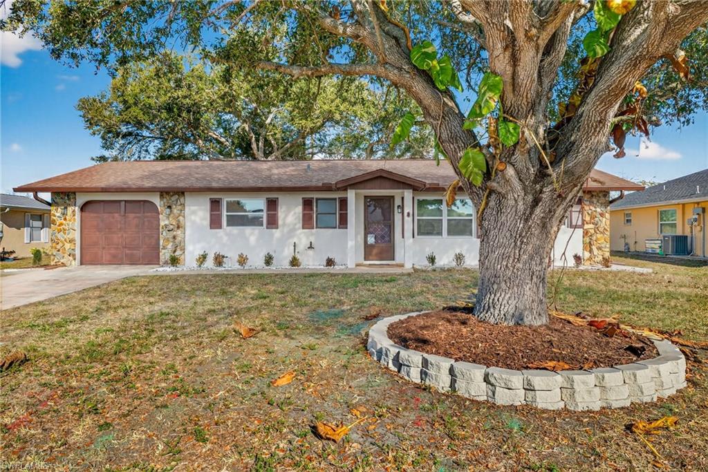 Ranch-style house featuring stone siding, an attached garage, driveway, and a front yard
