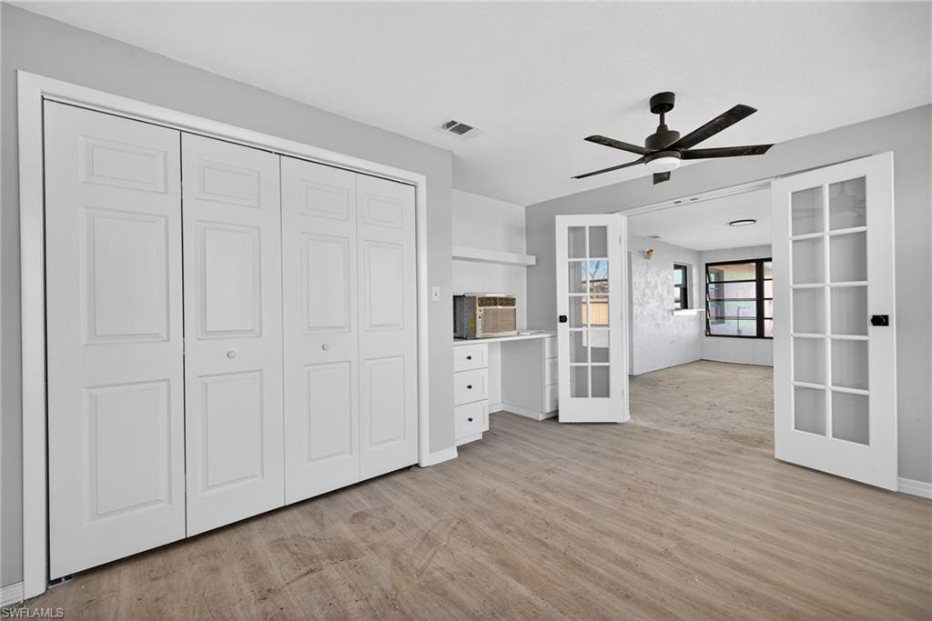 Unfurnished bedroom with built in desk, light wood-type flooring, french doors, and a closet