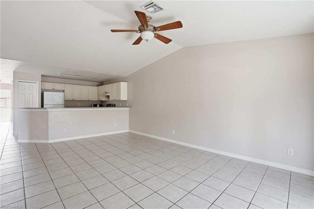 Unfurnished living room featuring a ceiling fan, light tile patterned floors, and lofted ceiling