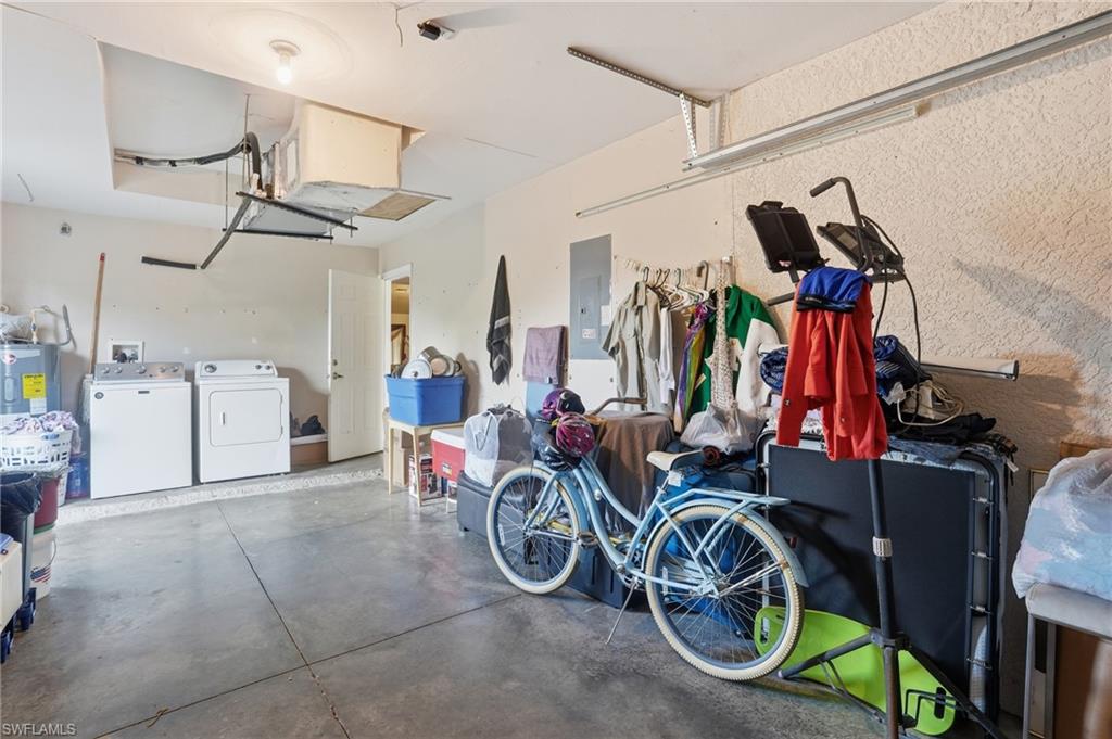 Garage with water heater, electric panel, and separate washer and dryer