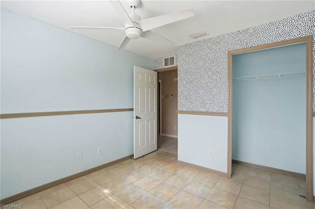 Unfurnished bedroom with ceiling fan, a closet, and wallpapered walls