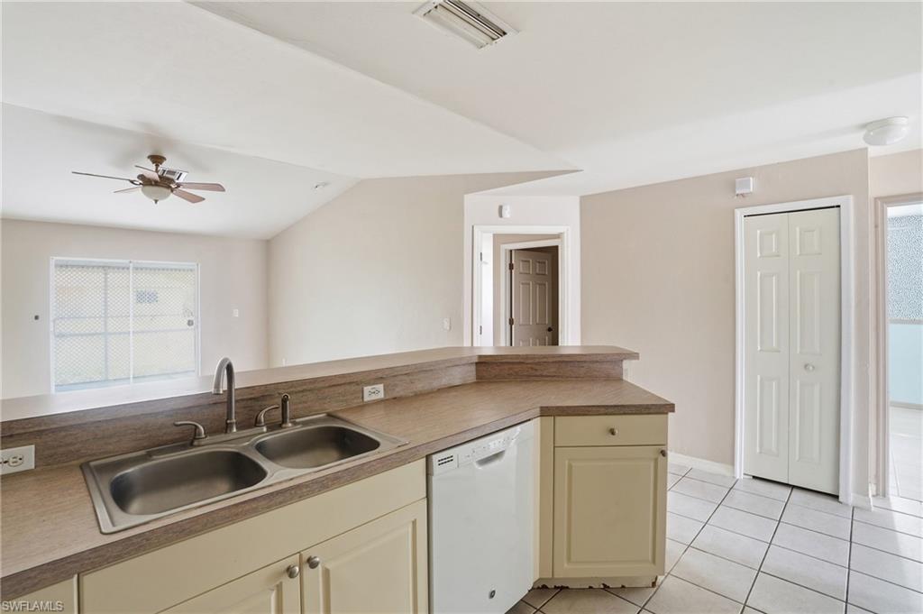 Kitchen featuring dishwasher, ceiling fan, cream cabinetry, light tile patterned floors, and light countertops