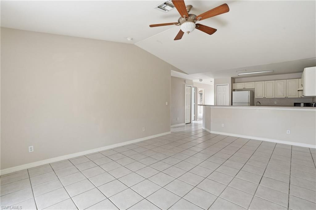 Unfurnished living room featuring a ceiling fan, lofted ceiling, and light tile patterned flooring
