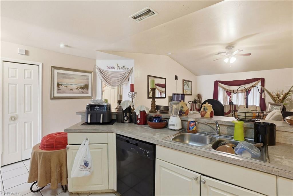 Kitchen featuring dishwasher, light countertops, ceiling fan, lofted ceiling, and light tile patterned flooring