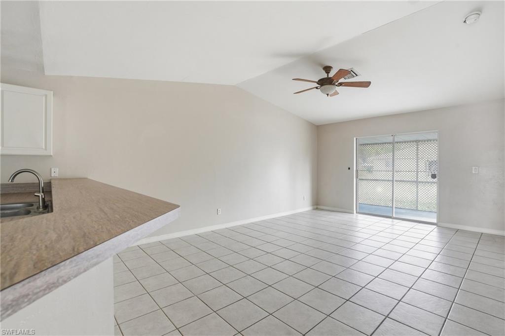 Unfurnished room featuring a ceiling fan, light tile patterned flooring, and vaulted ceiling