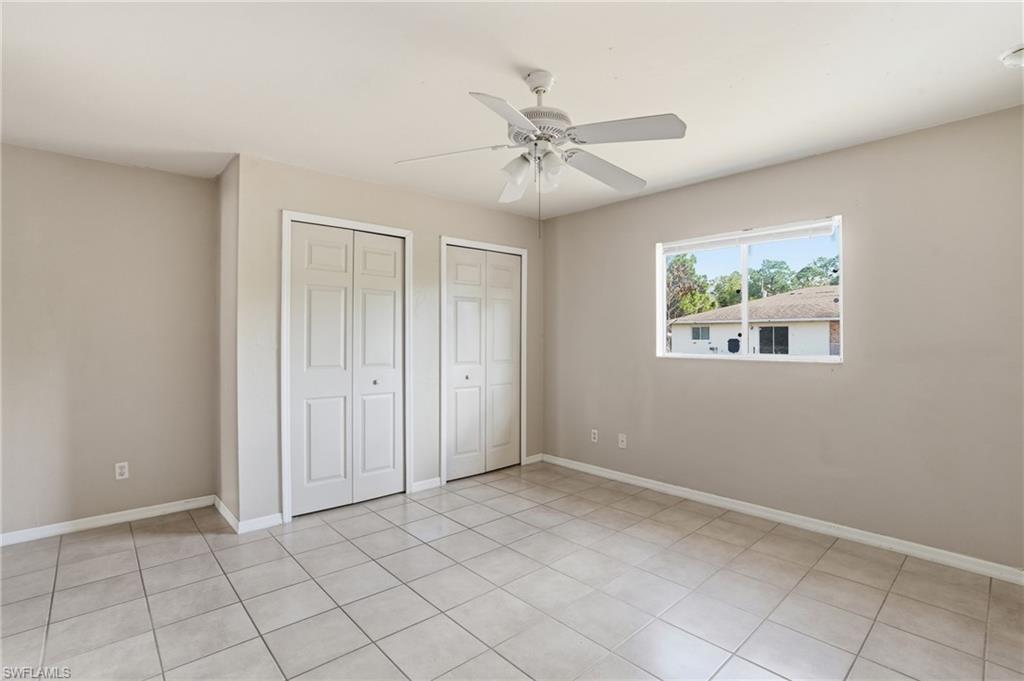 Unfurnished bedroom featuring two closets, a ceiling fan, and light tile patterned floors