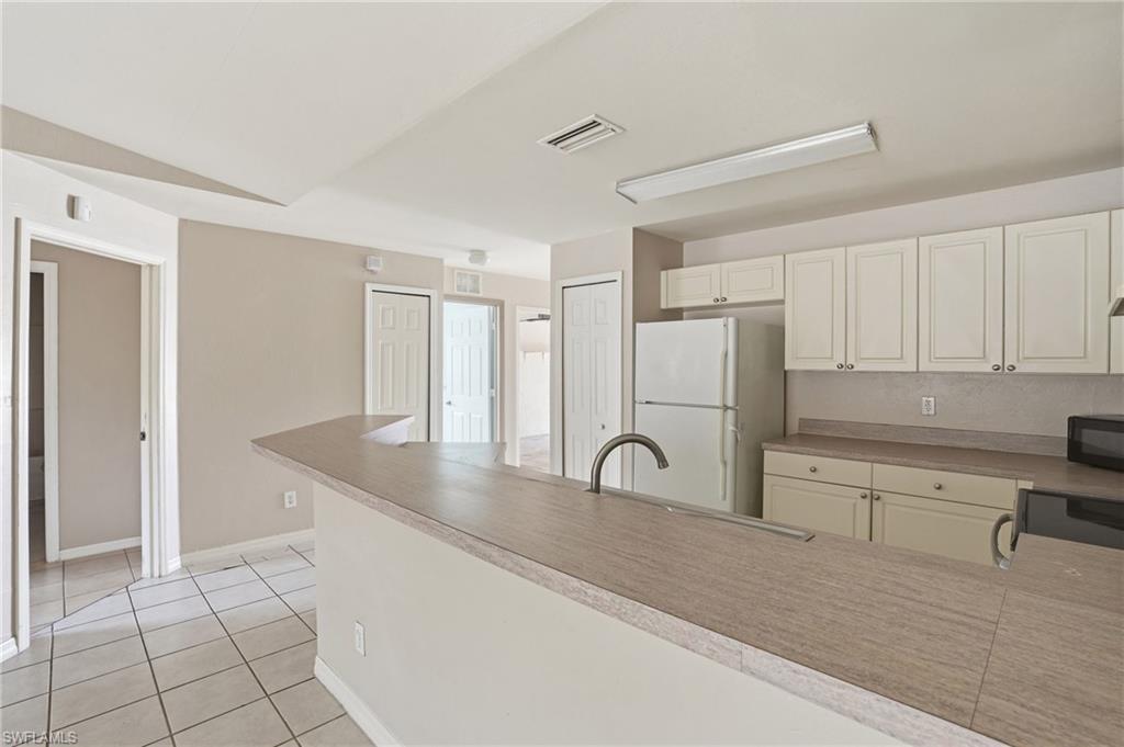 Kitchen featuring black appliances, light tile patterned floors, a peninsula, and light countertops