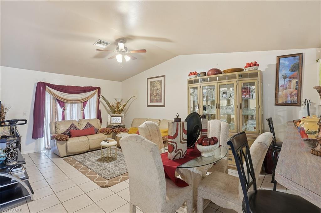 Dining area featuring lofted ceiling, light tile patterned floors, and a ceiling fan