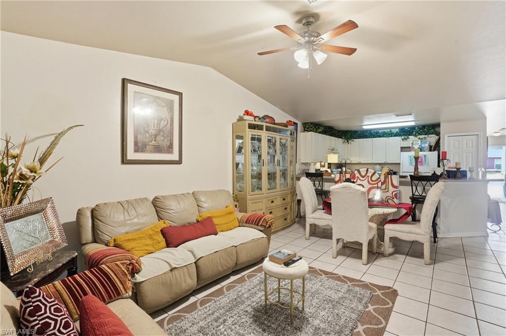 Living room featuring ceiling fan, vaulted ceiling, and light tile patterned floors
