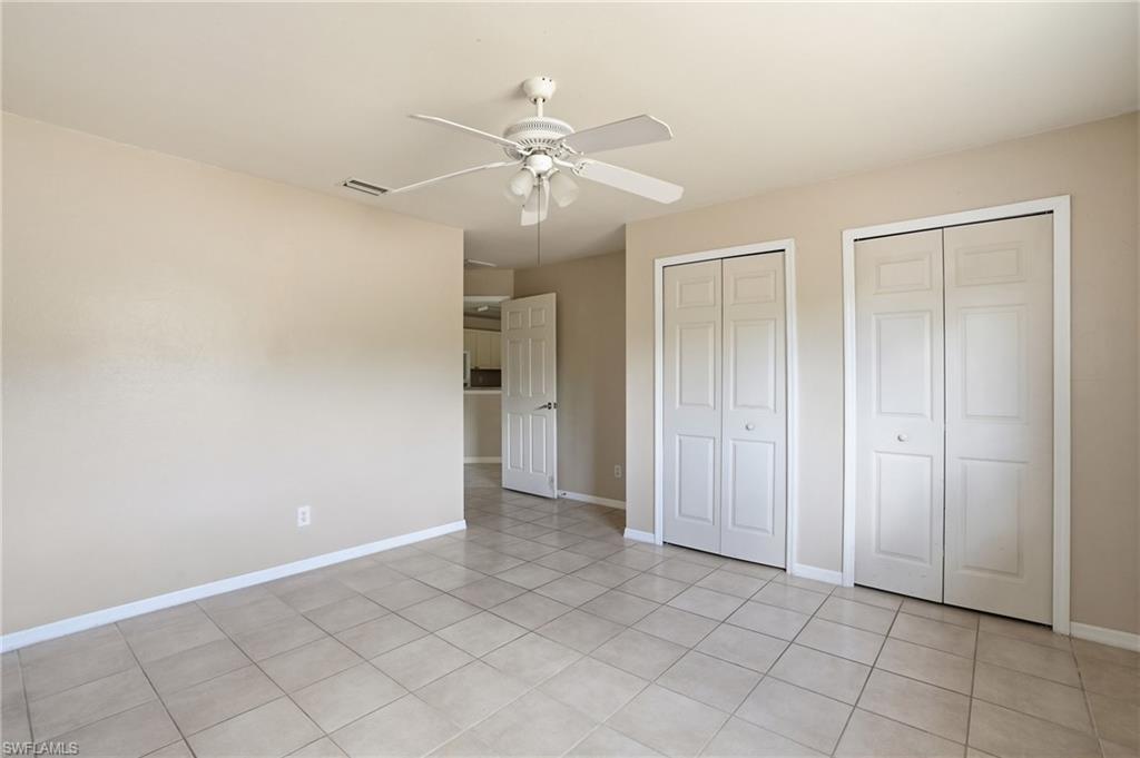 Unfurnished bedroom with multiple closets, ceiling fan, and light tile patterned floors