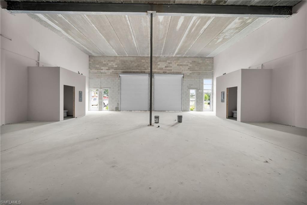 Spacious open floor plan with polished concrete flooring, exposed beam ceiling structure, and abundant natural light from multiple windows