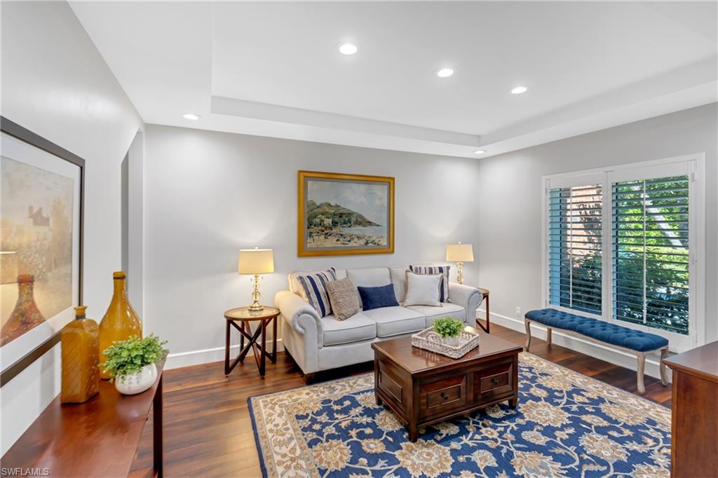 Living room featuring recessed lighting, dark wood-type flooring, and a raised ceiling