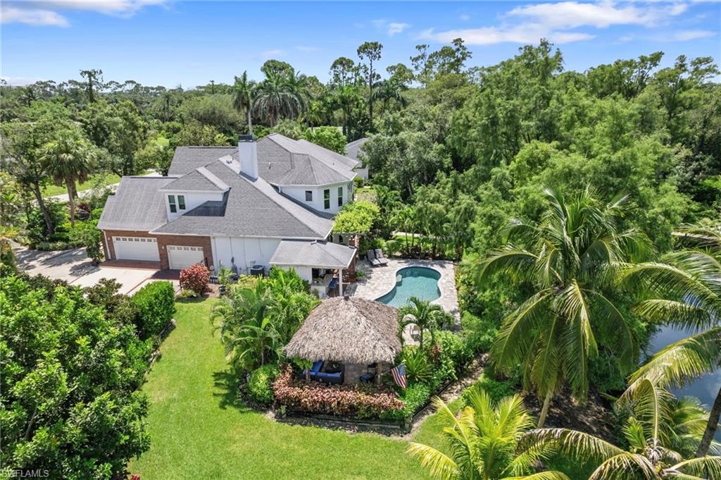 Aerial view of property and surrounding area with a tree filled landscape and a pool