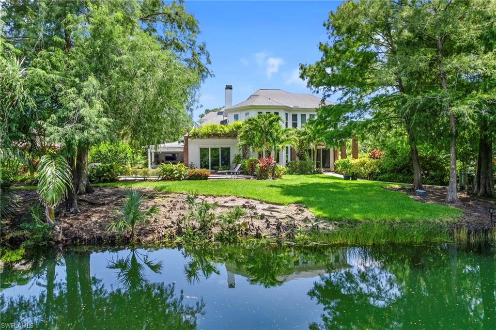 Back of property with a lawn, a chimney, and a water view