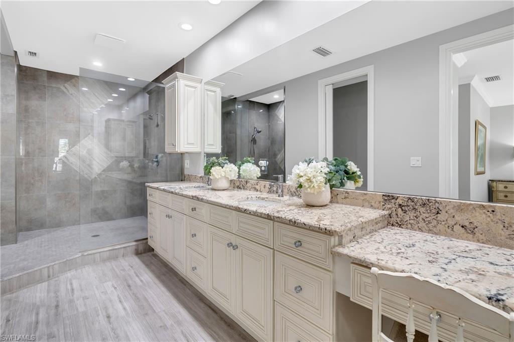 Full bathroom featuring a walk in shower, double vanity, light wood finished floors, and recessed lighting