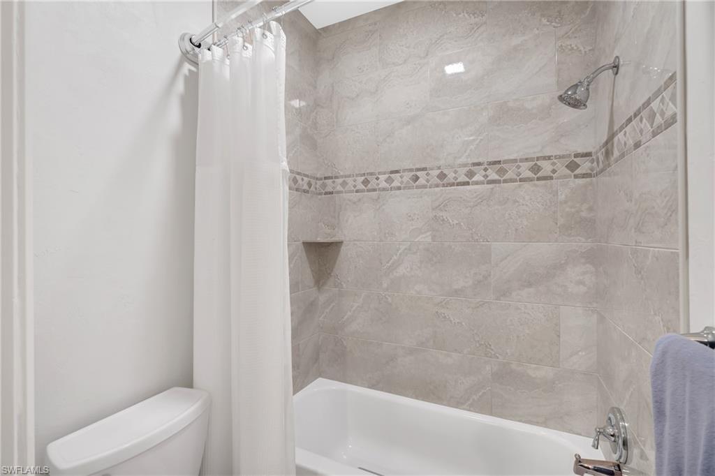 Bathroom with shower / bath combination with curtain and toilet