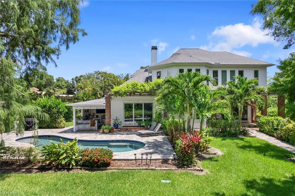 Back of property featuring a lawn, a chimney, an outdoor pool, and a patio area