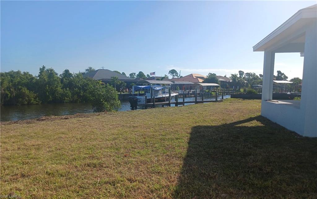 Expansive waterfront lot featuring a private dock with covered boat slips, direct canal access, and established mangroves