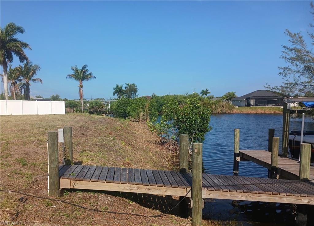 Waterfront property featuring a wooden dock, direct water access, and mature palm trees