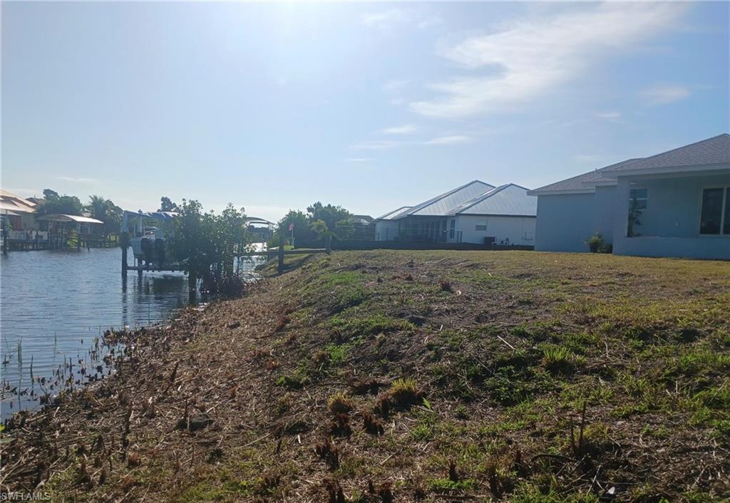 Expansive waterfront lot featuring direct canal access, a sloped bank, and partial clear land