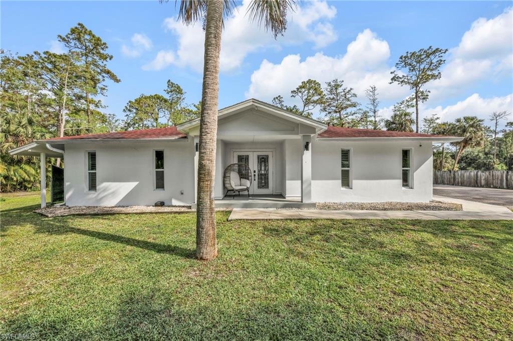 Rear view of property featuring stucco siding, french doors, and a lawn