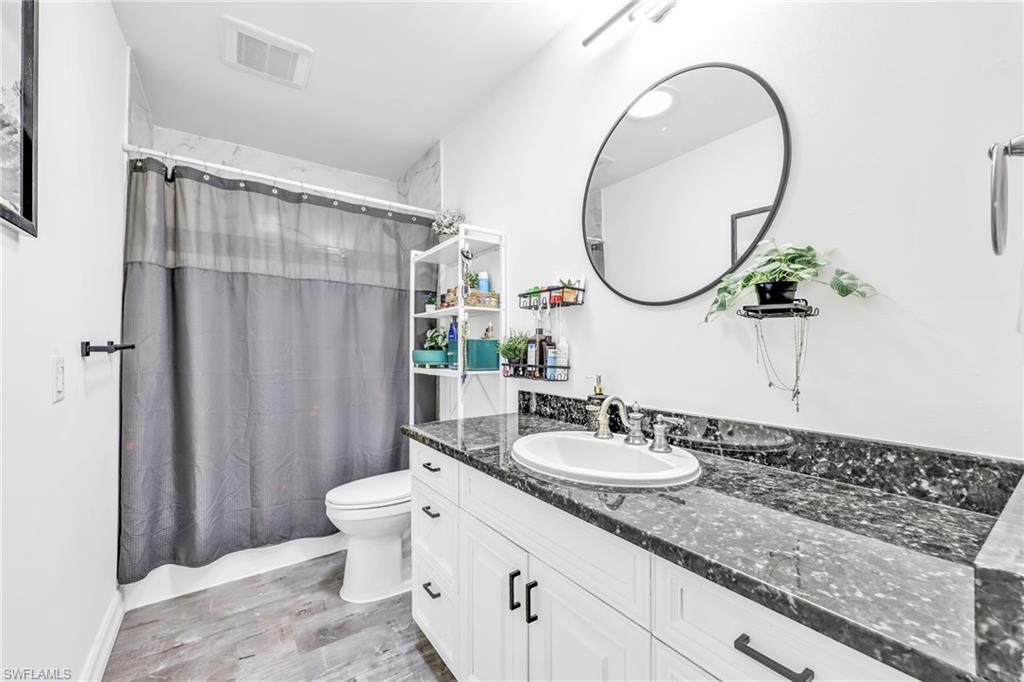 Full bath with vanity, light wood-style floors, and shower / bath combination with curtain