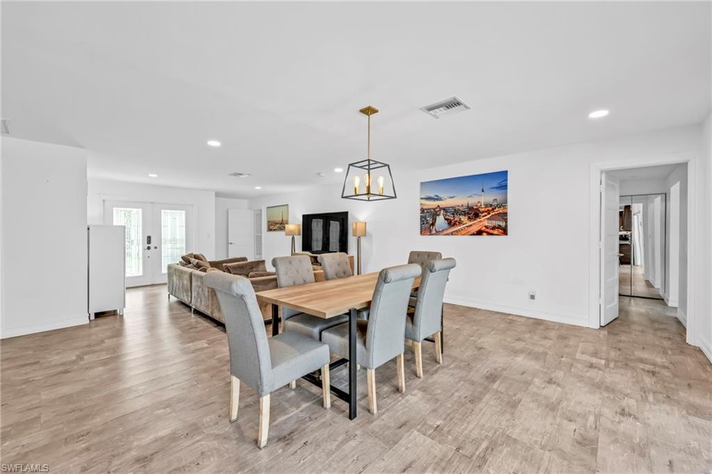 Dining area with light wood-type flooring, suspended lighting, and french doors