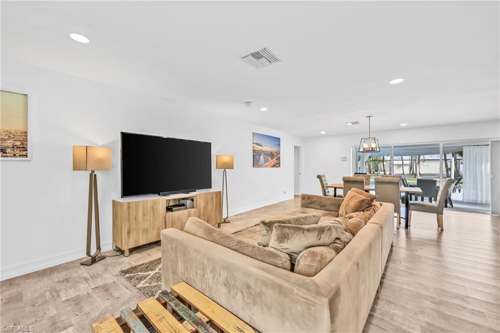 Living area with light wood-type flooring and suspended lighting