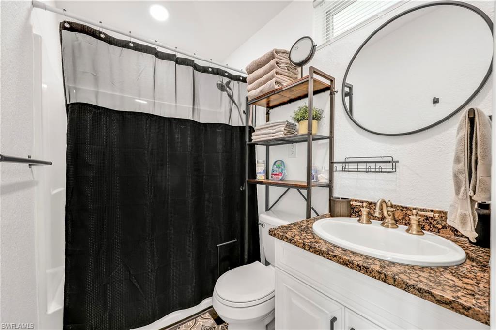 Full bathroom with curtained shower, a textured wall, and vanity