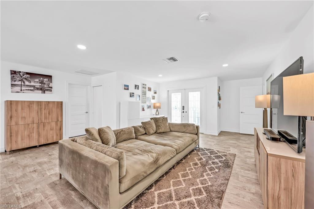 Living room with light wood finished floors, french doors, and recessed lighting