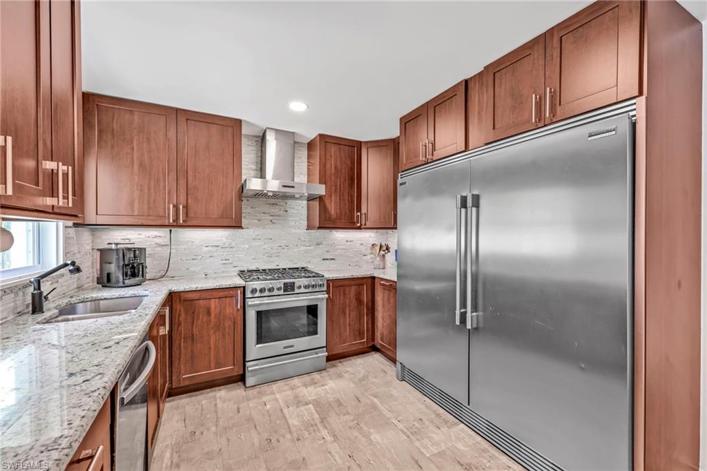 Kitchen with stainless steel appliances, light stone countertops, backsplash, light wood-type flooring, and recessed lighting
